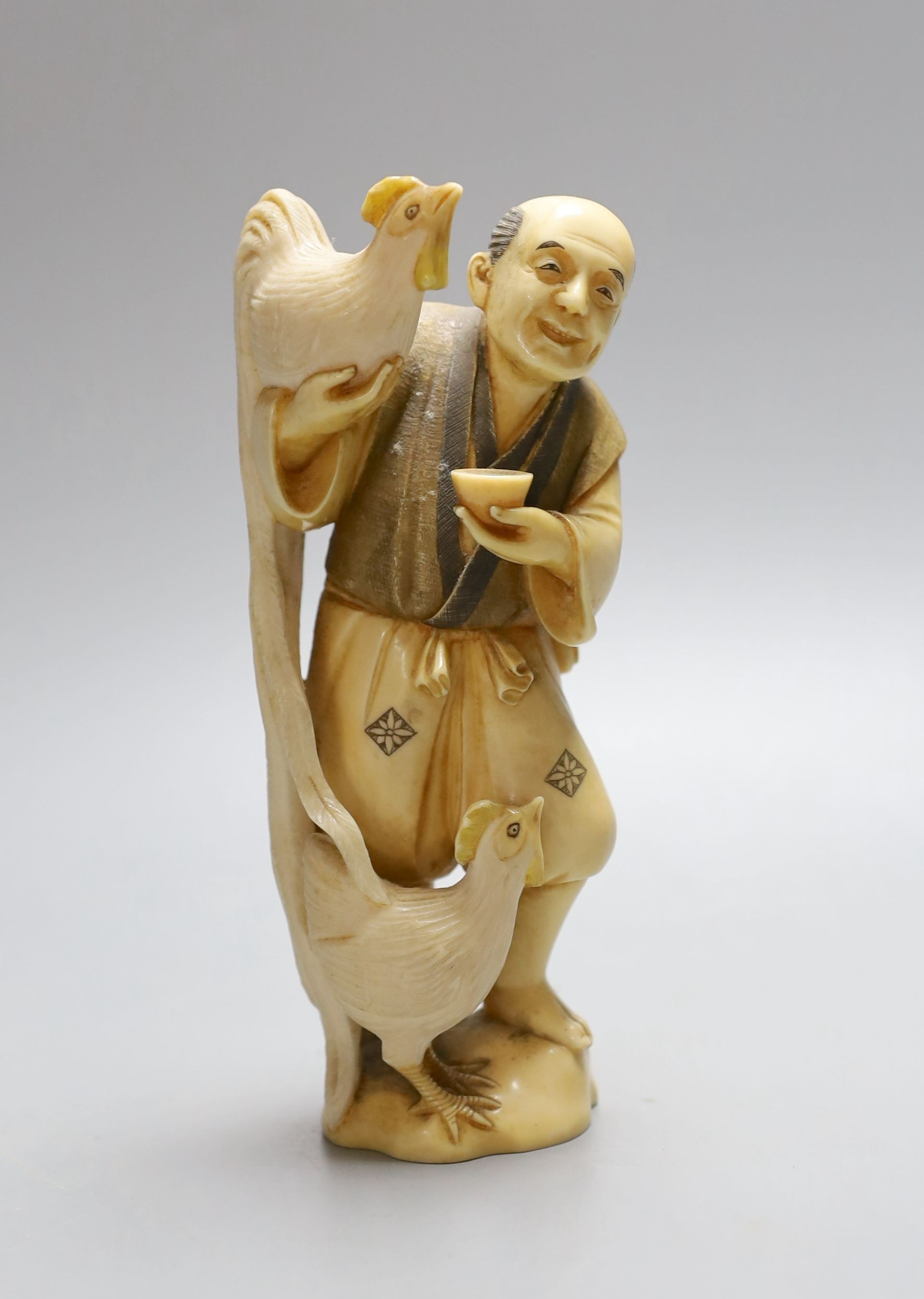 A Japanese ivory okimono figure of man with chicken, early 20th century, signed inset tablet to base - 16cm high